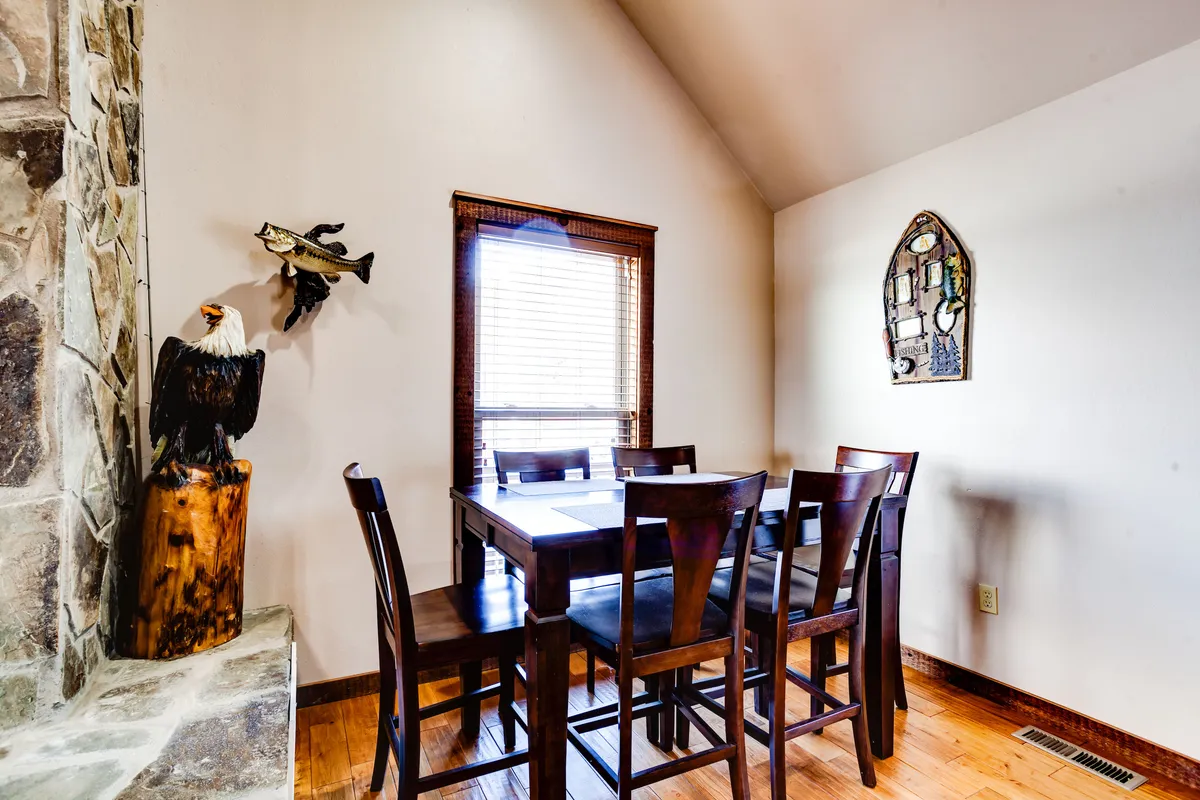 A cozy dining area featuring a rustic wooden table, an eagle sculpture, fish-themed wall decor, and colorful stained glass art. The space is filled with natural light and exudes a warm, welcoming atmosphere, suggesting a strong connection to the region’s wildlife and outdoor culture.