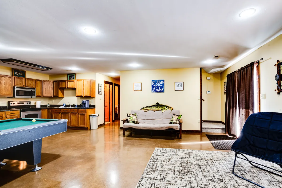 A friendly, relaxed game room scene featuring a pool table, a comfortable sofa for lounging, a kitchen area, and lively decorative wall signs. The open layout invites socializing, playing games, and enjoying snacks, aligning with the section's theme of entertainment and connection.